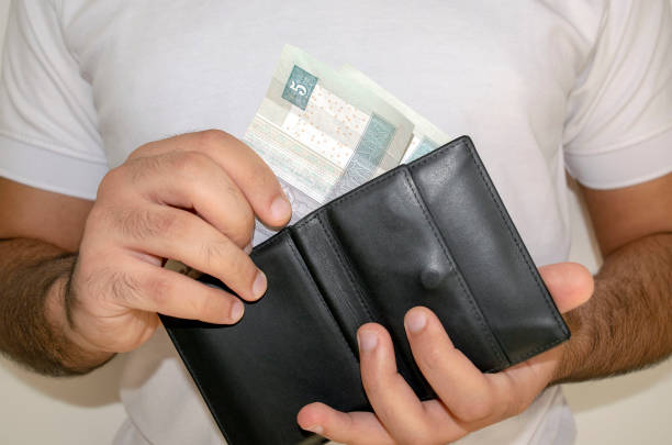 istock Man in white t shirt put egyptian pound banknotes into black wallet. 1221628646