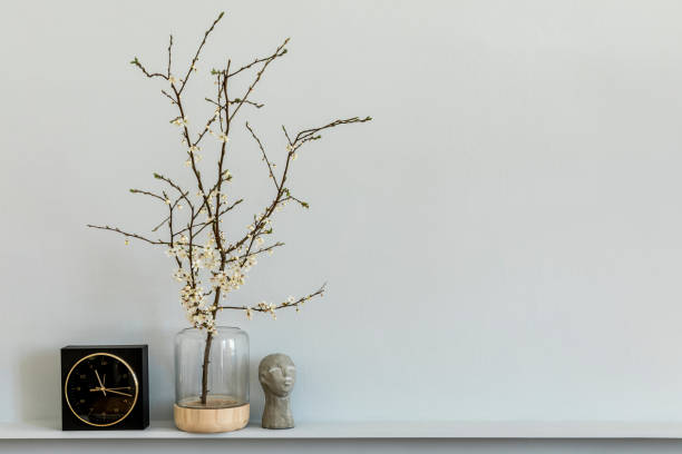 istock Minimalistic composition on the shelf with dried flower in design vase, black clock and decoration. Grey wall. Copy space. 1221630905
