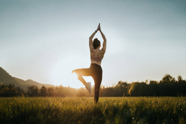 istock Young woman doing yoga on a field at sunset 1221630965