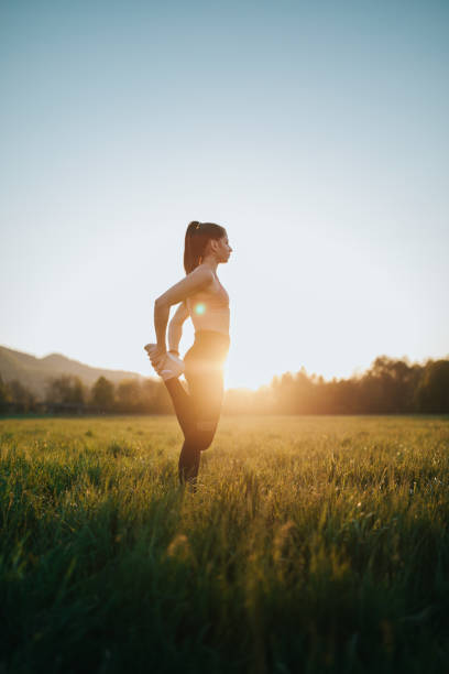 Young woman stretching outdoors on a field at sunset