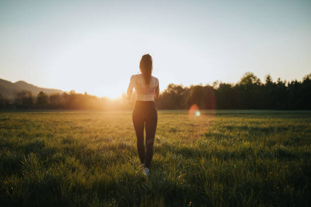 istock Young woman running through the field at sunset 1221631362