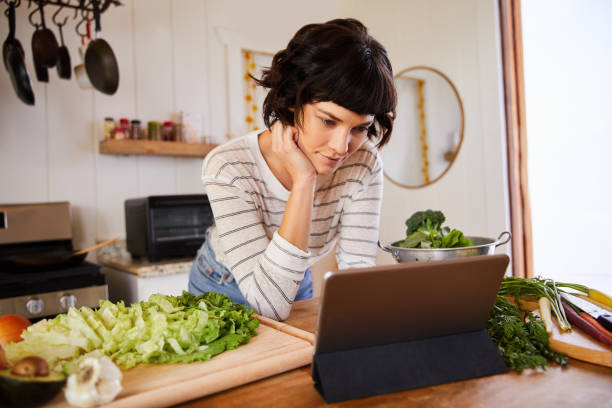 istock Young woman preparing dinner from recipe on her tablet 1221631492