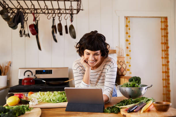 istock Smiling young woman making dinner from recipe on her tablet 1221631620