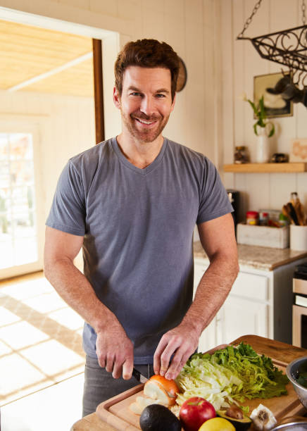 istock Smiling man chopping fresh vegetables in his kitchen at home 1221633012
