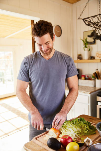 istock Smiling man standing in his kitchen chopping fresh vegetables for dinner 1221633091