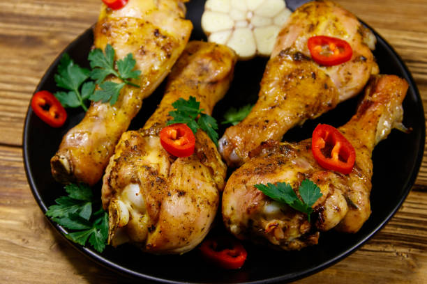 istock Roasted chicken drumsticks with spices in a black plate on a wooden table 1221633143