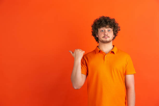 istock Caucasian young man's monochrome portrait on orange studio background 1221634618