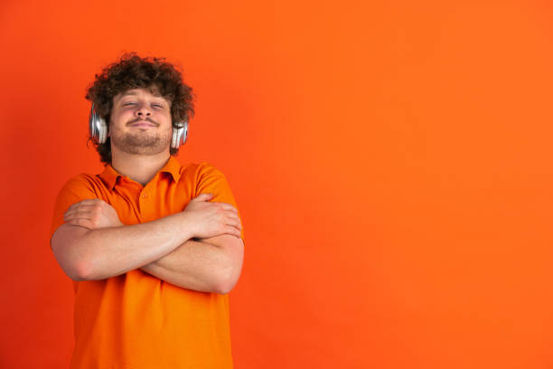 istock Caucasian young man's monochrome portrait on orange studio background 1221634626