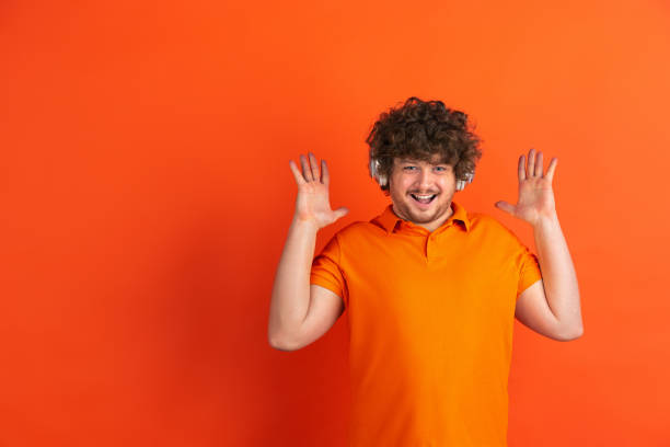 istock Caucasian young man's monochrome portrait on orange studio background 1221634628
