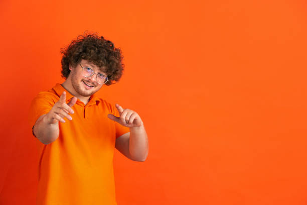 istock Caucasian young man's monochrome portrait on orange studio background 1221634635