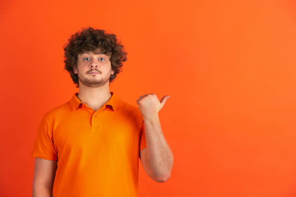 istock Caucasian young man's monochrome portrait on orange studio background 1221634638