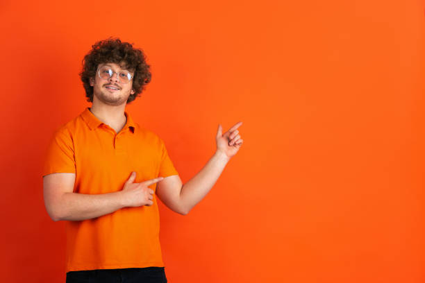 istock Caucasian young man's monochrome portrait on orange studio background 1221634642