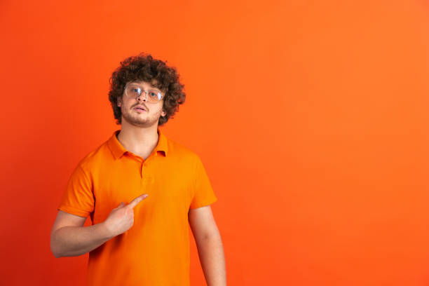 istock Caucasian young man's monochrome portrait on orange studio background 1221634647