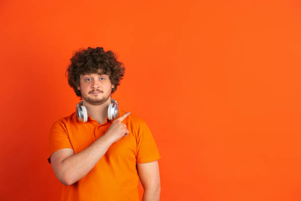 Caucasian young man's monochrome portrait on orange studio background