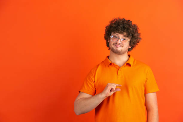 istock Caucasian young man's monochrome portrait on orange studio background 1221634661