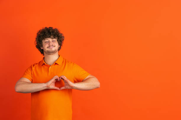 istock Caucasian young man's monochrome portrait on orange studio background 1221634664