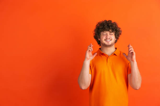 istock Caucasian young man's monochrome portrait on orange studio background 1221634668