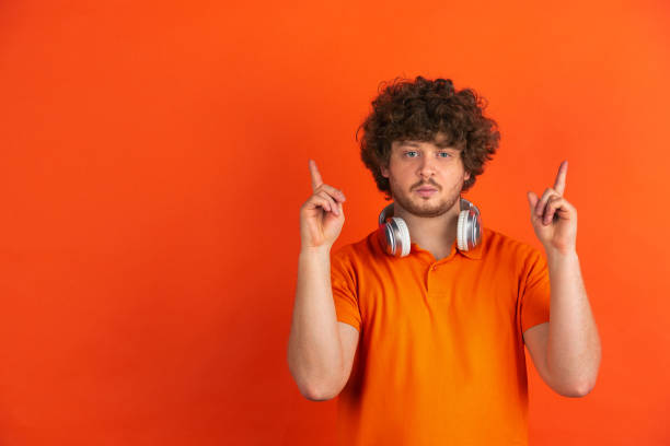 istock Caucasian young man's monochrome portrait on orange studio background 1221634669