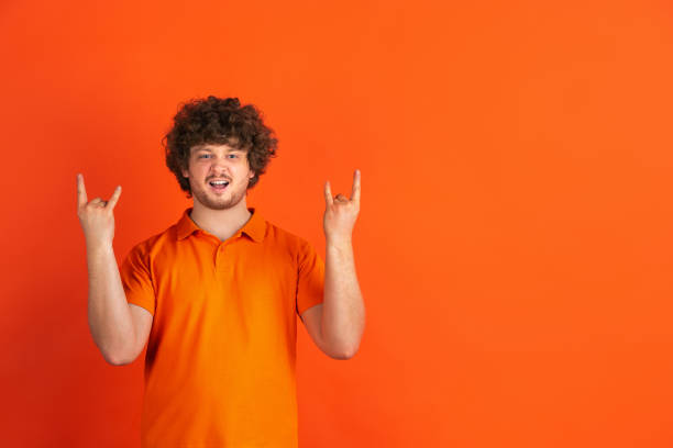 Caucasian young man's monochrome portrait on orange studio background