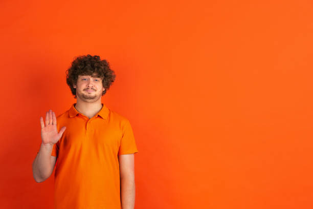 istock Caucasian young man's monochrome portrait on orange studio background 1221634697