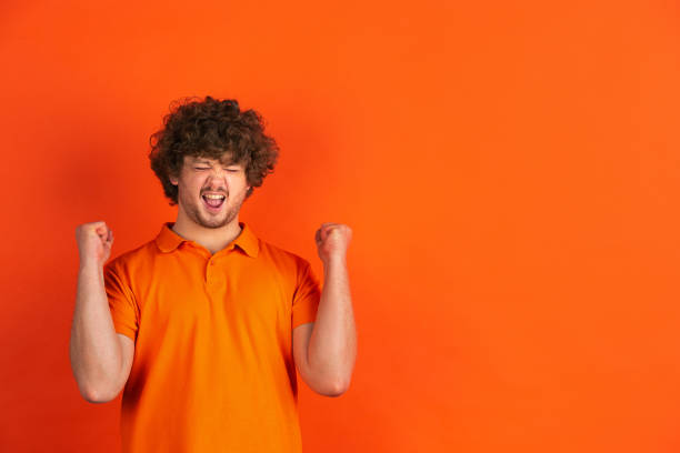 istock Caucasian young man's monochrome portrait on orange studio background 1221634698