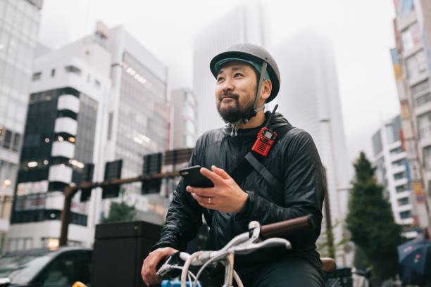 Happy Bike Messenger Bicycle Messenger checking for directions on the phone. home delivery photos stock pictures, royalty-free photos & images