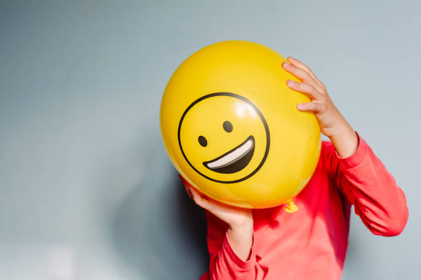 criança segurando balão amarelo nas mãos - child smiley face smiling happiness - fotografias e filmes do acervo