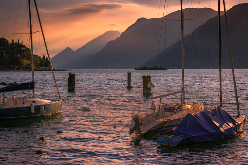 Yachts and sailboats on Lake Garda and Trentino alps near Malcesine at sunset, Italy