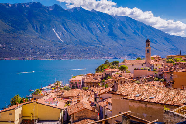 イタリア、リモーネ・スル・ガルダの上のガルダ湖とトレンティーノのアルプス - lake garda sunset blue nautical vessel ストックフォトと画像