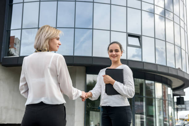 istock Two business women in suits handshaking before office building 1221637029