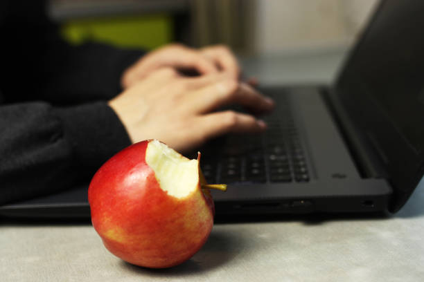 istock Young woman working on laptop on kitchen table, remote work at home, self-isolation, selective focus on Apple 1221638316