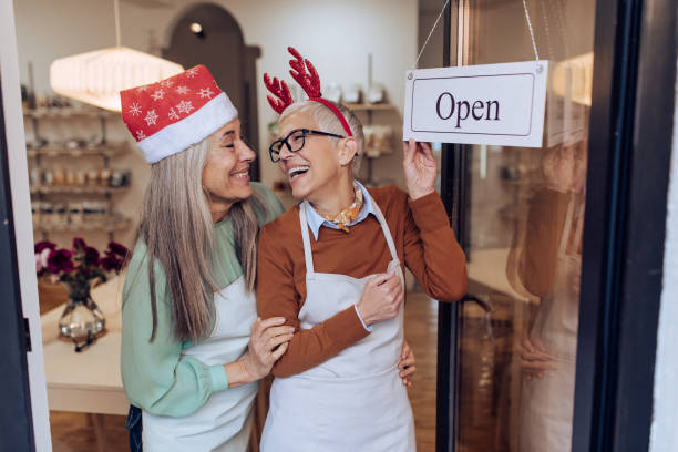 excited mature colleagues opening their store for christmas - sales clerk store manual worker retail imagens e fotografias de stock