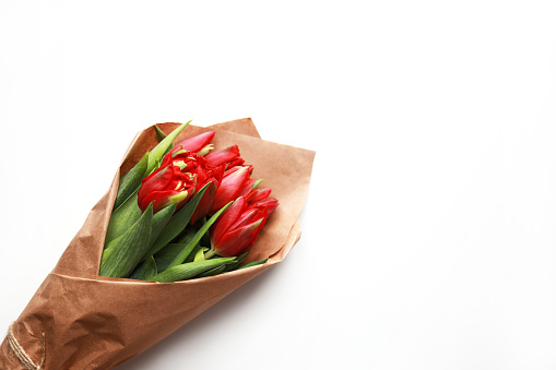 Beautiful bouquet made of red tulips in craft paper. Flat lay on white isolated background. Mother's day, International woman's day, Valentine's day greeting.