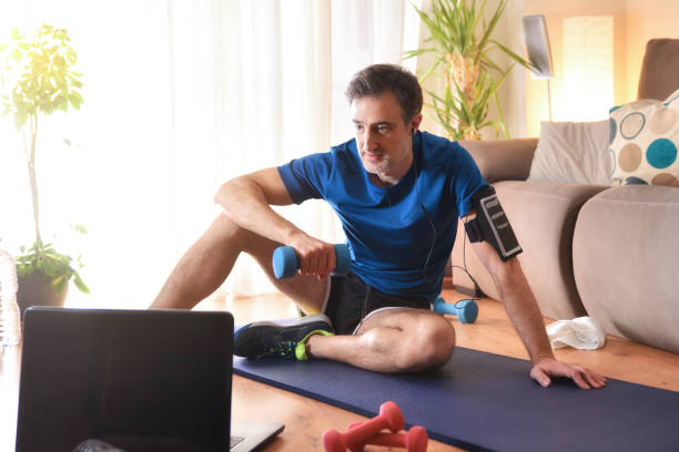 homem fazendo esportes assistindo vídeos em um laptop em casa - short phrase audio - fotografias e filmes do acervo