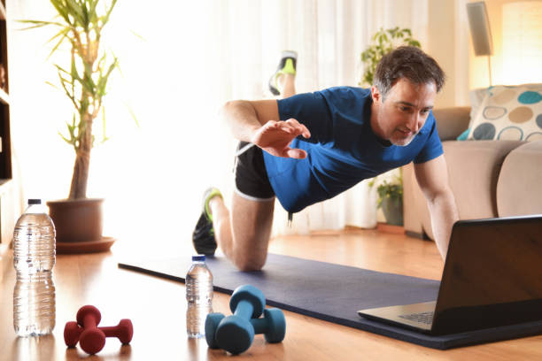 istock Man doing sports looking at a laptop at home 1221641420