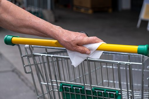 Senior Man Hands Close Up disinfecting handle from shopping cart