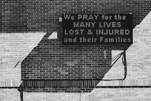 An led sign reads 'We pray for the many lives lost & injured and their families' in the aftermath of a mass shooting in April 2020.