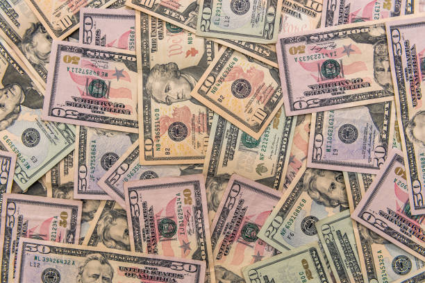 istock Dollar banknotes dispersed on wooden table close up 1221644192