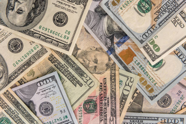istock Dollar banknotes dispersed on wooden table close up 1221644486