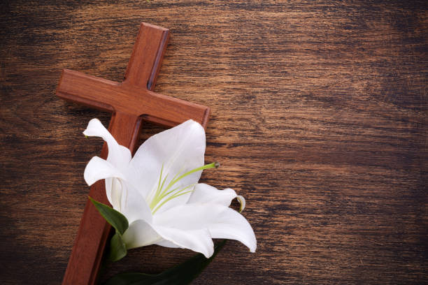 istock Wooden cross and white lily on rustic table 1221644755