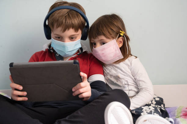 istock Brother and sister with masks at home 1221645901