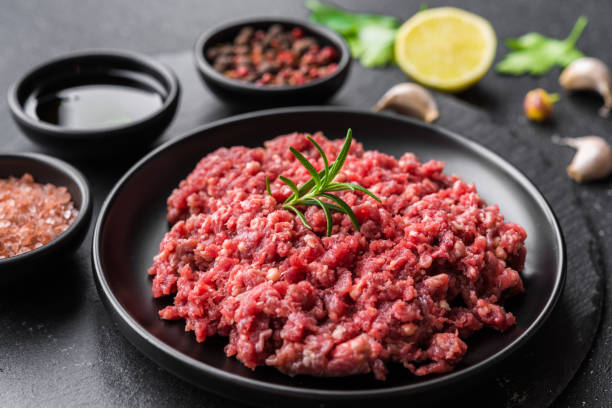 Fresh minced meat ground beef on a black plate against stone background stock photo