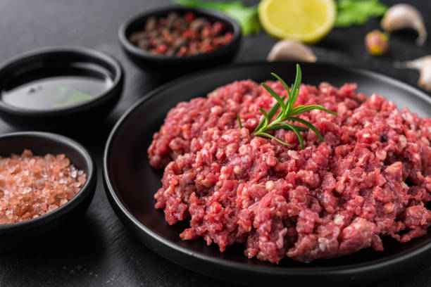 carne macinata fresca macinata su un piatto nero su sfondo di pietra - ground beef foto e immagini stock
