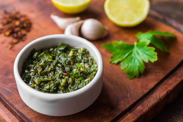 Traditional Argentinian chimichurri sauce against wooden background stock photo