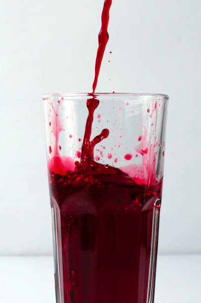 istock Splashing liquid red pomegranate and grape juice pouring into a glass 1221646447