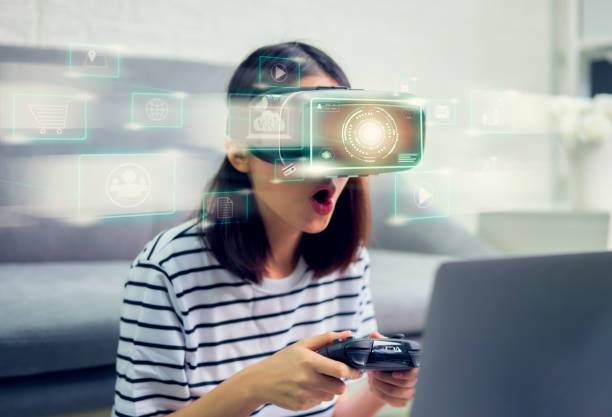 Concept connection and interfaces of digital technology, Excited young Asian woman using a virtual reality headset and joysticks, beautiful light with color lines.