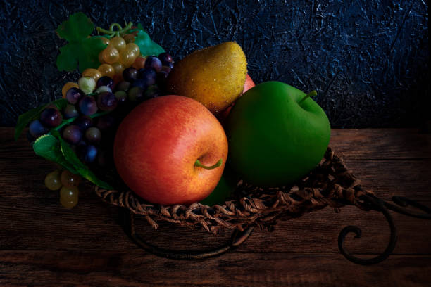 Artificial fruits lie in a wicker basket. Still life with dark lighting. Background