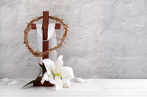 Composition with crown of thorns, cross and lily on light background