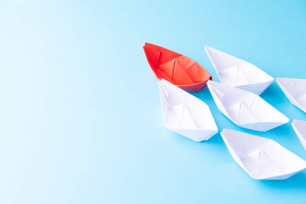 istock A red ship as a leader. White following it. Blue background 1221649980
