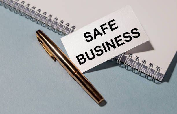 istock SAFE BUSINESS inscription on whte paper with white notebook and pen on blue grey table 1221651365